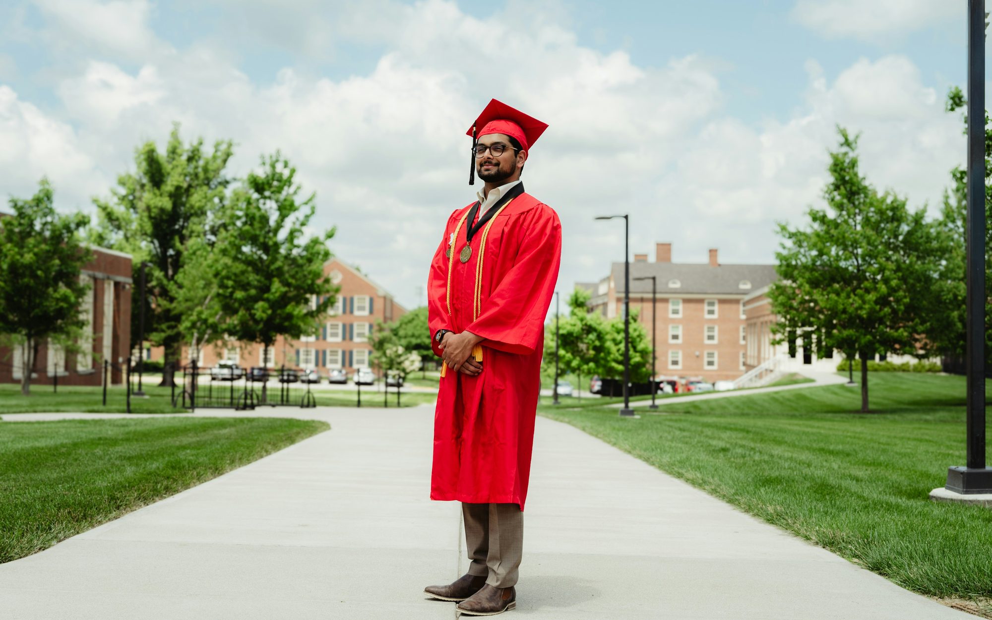 Graduate standing on a university campus path in cap and gown