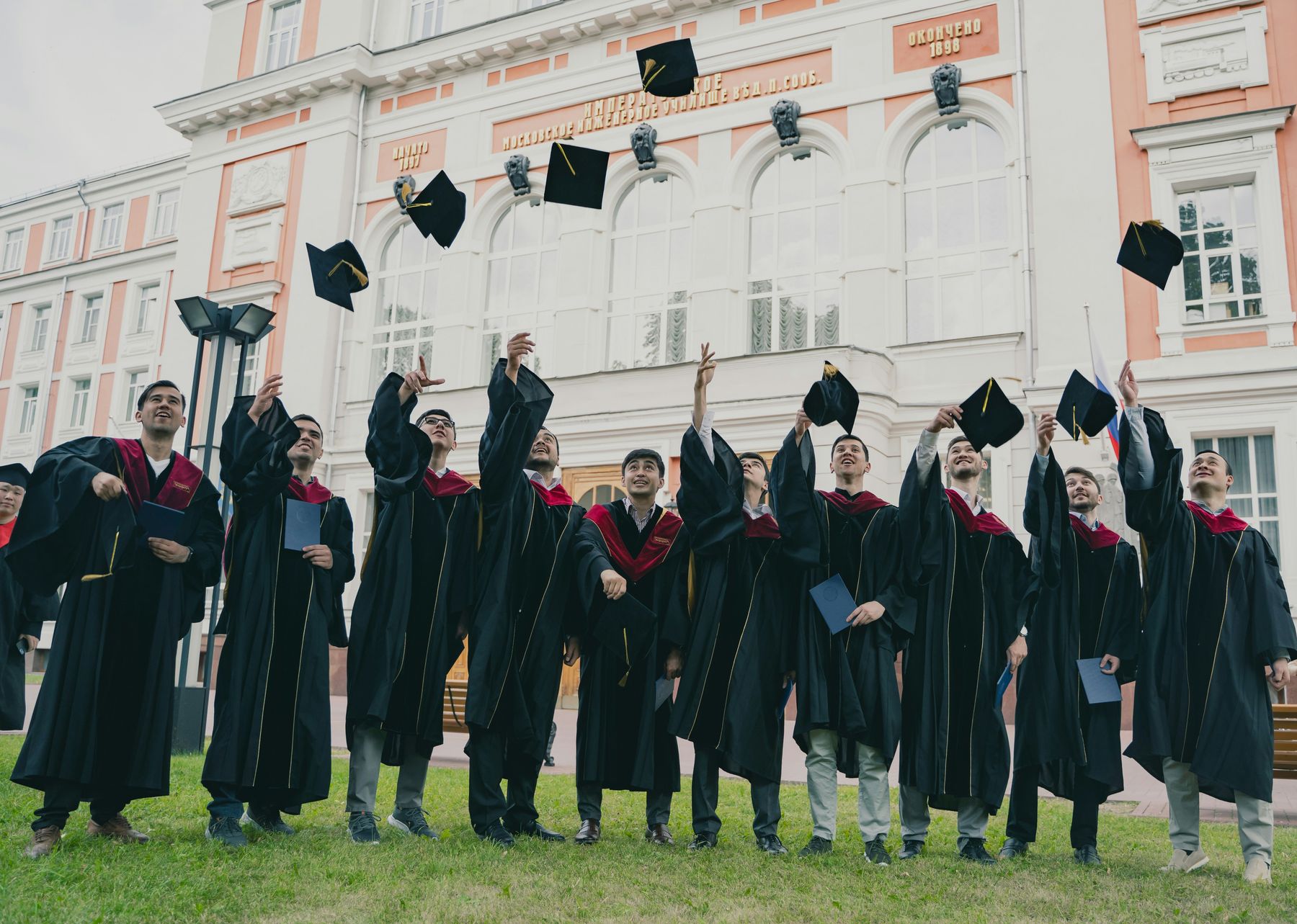 Graduates celebrating and throwing their caps outside their university